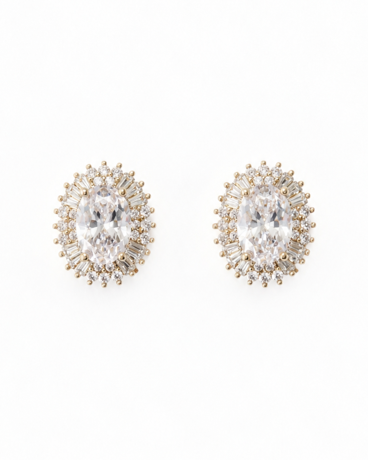A pair of oval stud earrings featuring a large clear central stone surrounded by smaller clear baguette and round stones in a yellow gold setting, shown on a plain white background.